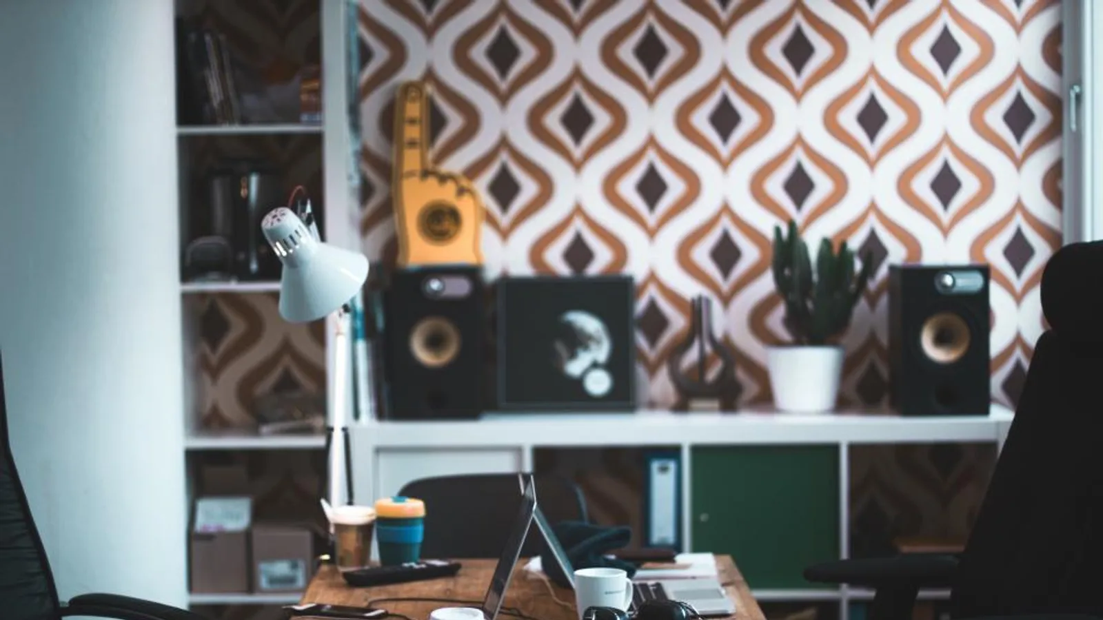 A designer’s studio desk in front of a boldly patterned brand wall.