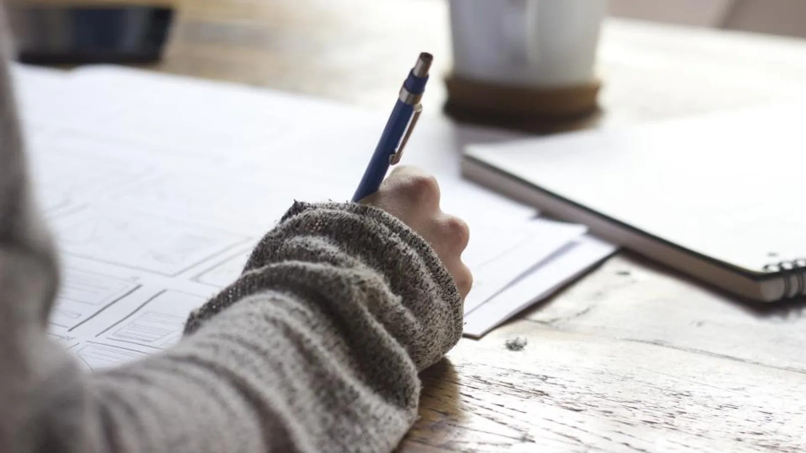 A person writing in a notebook at a desk.